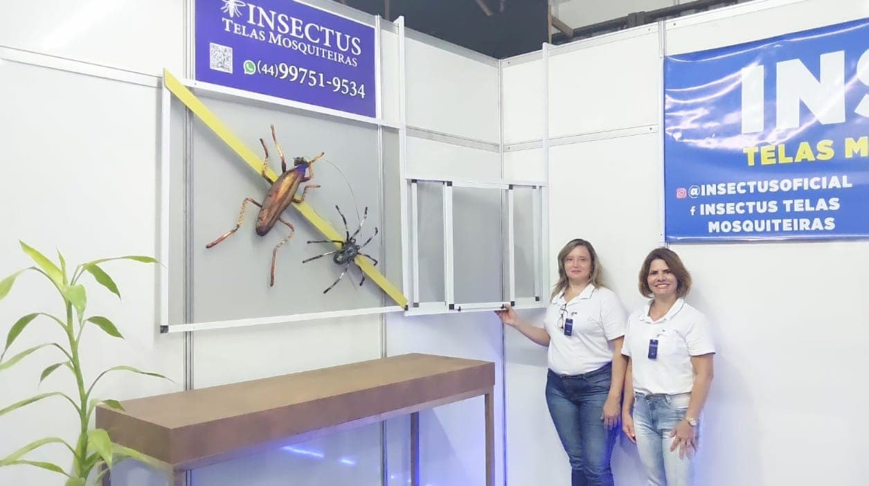 Duas pessoas da equipe da Insectus, de uniforme, no estande da empresa em feira do setor